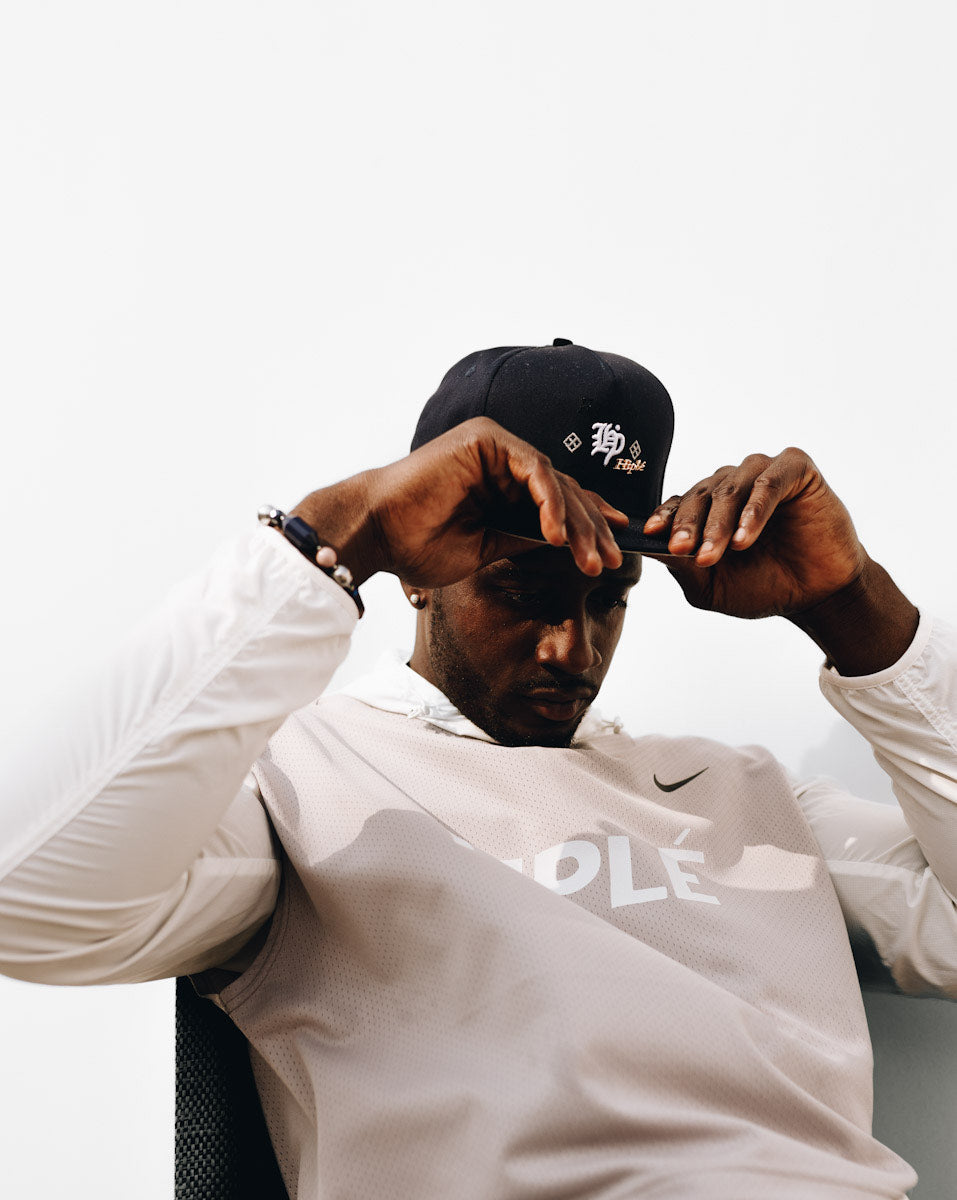 Person wearing a navy blue HipléStyle cap and white shirt with visible branding